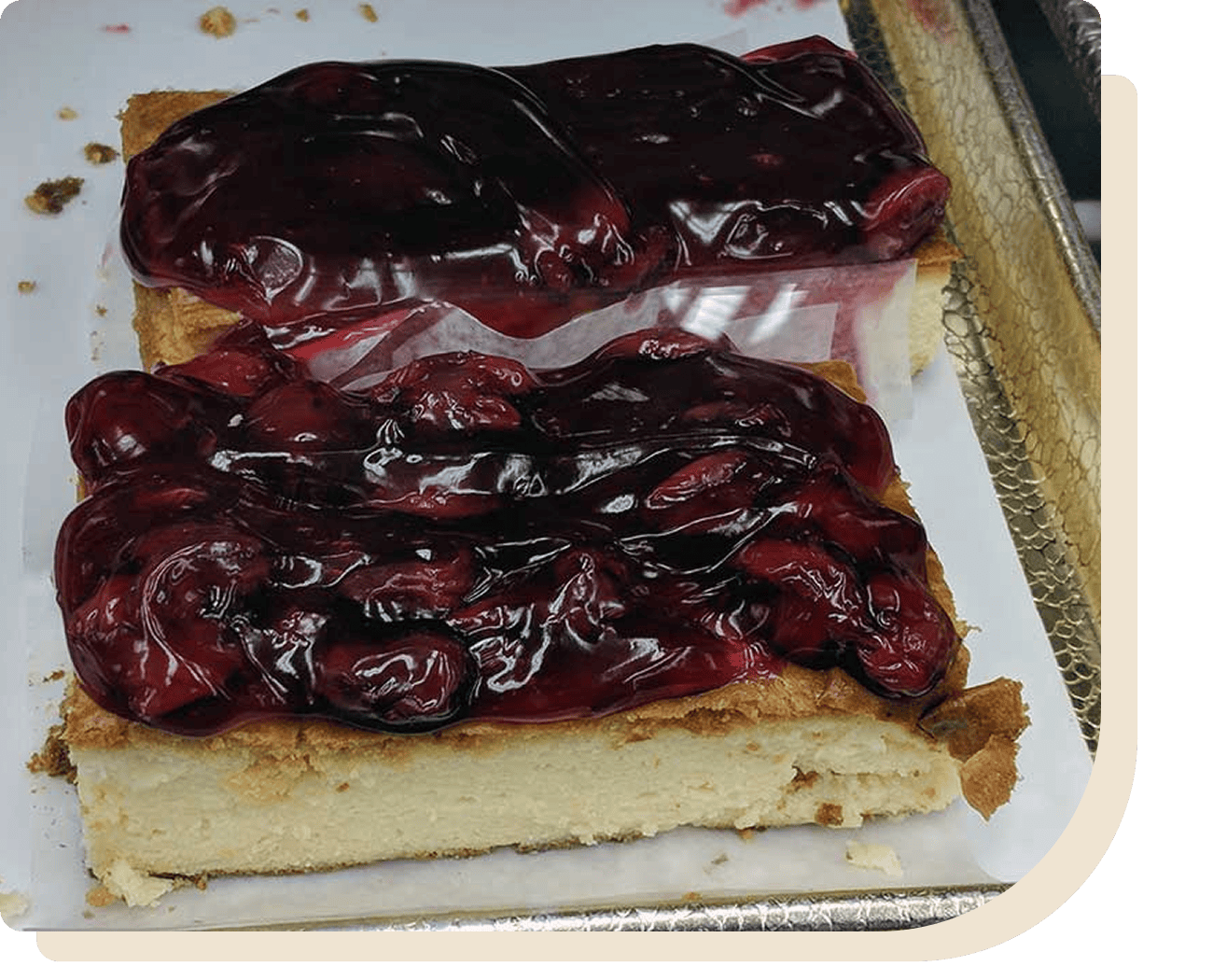 Piece of cheesecake with cherries on top of it, sitting on a tray